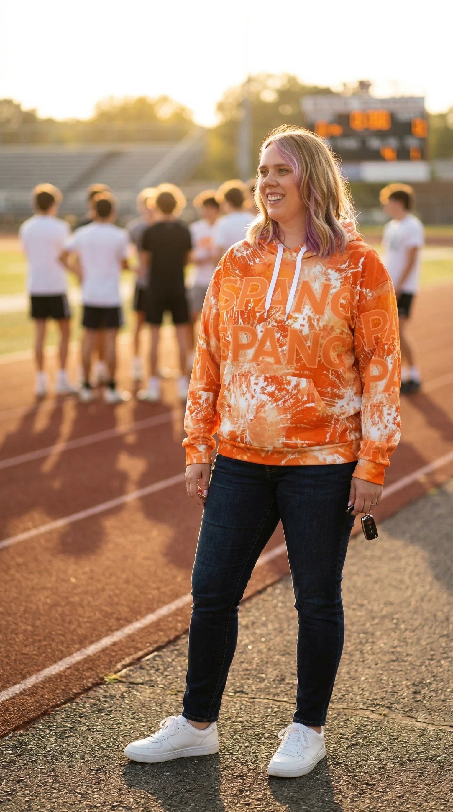 Person wearing a custom orange tie-dye hoodie with text on a track field