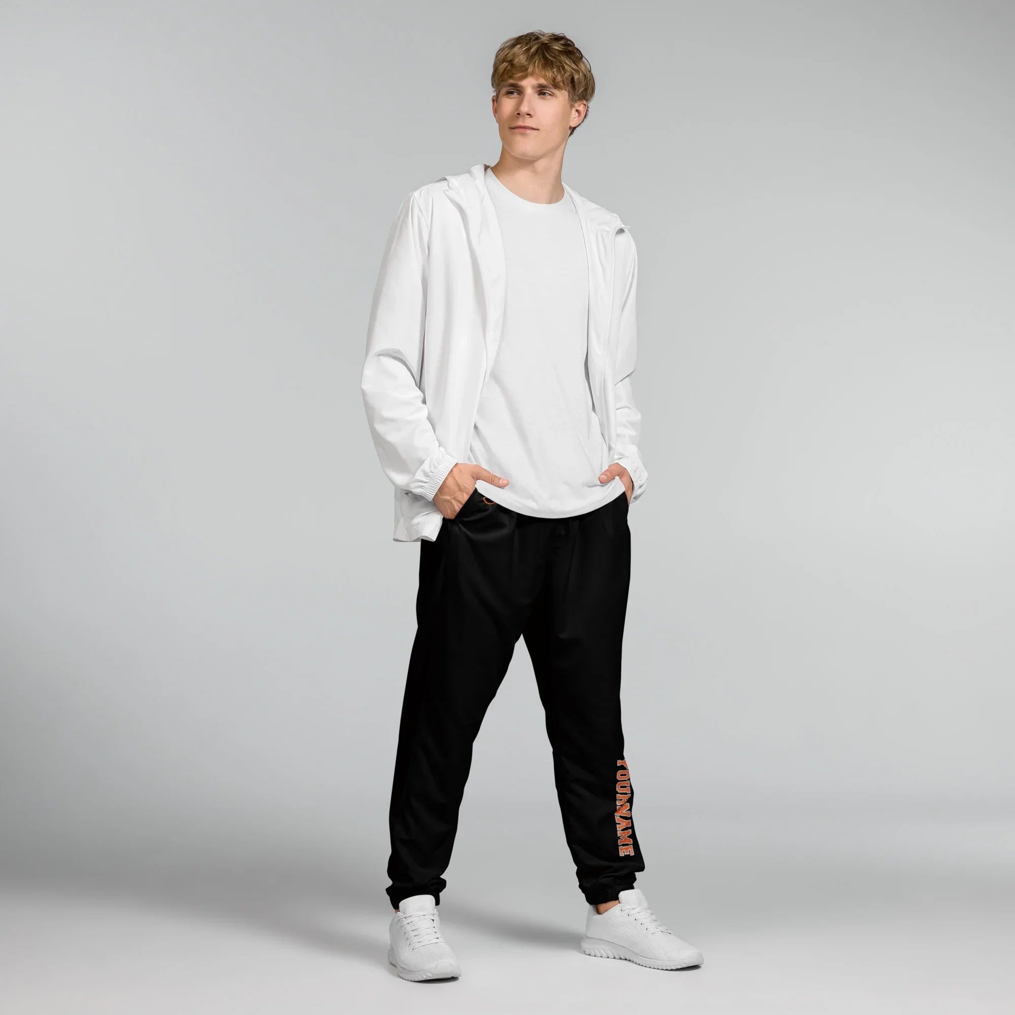 Person wearing a white hoodie and black pants on a gray background