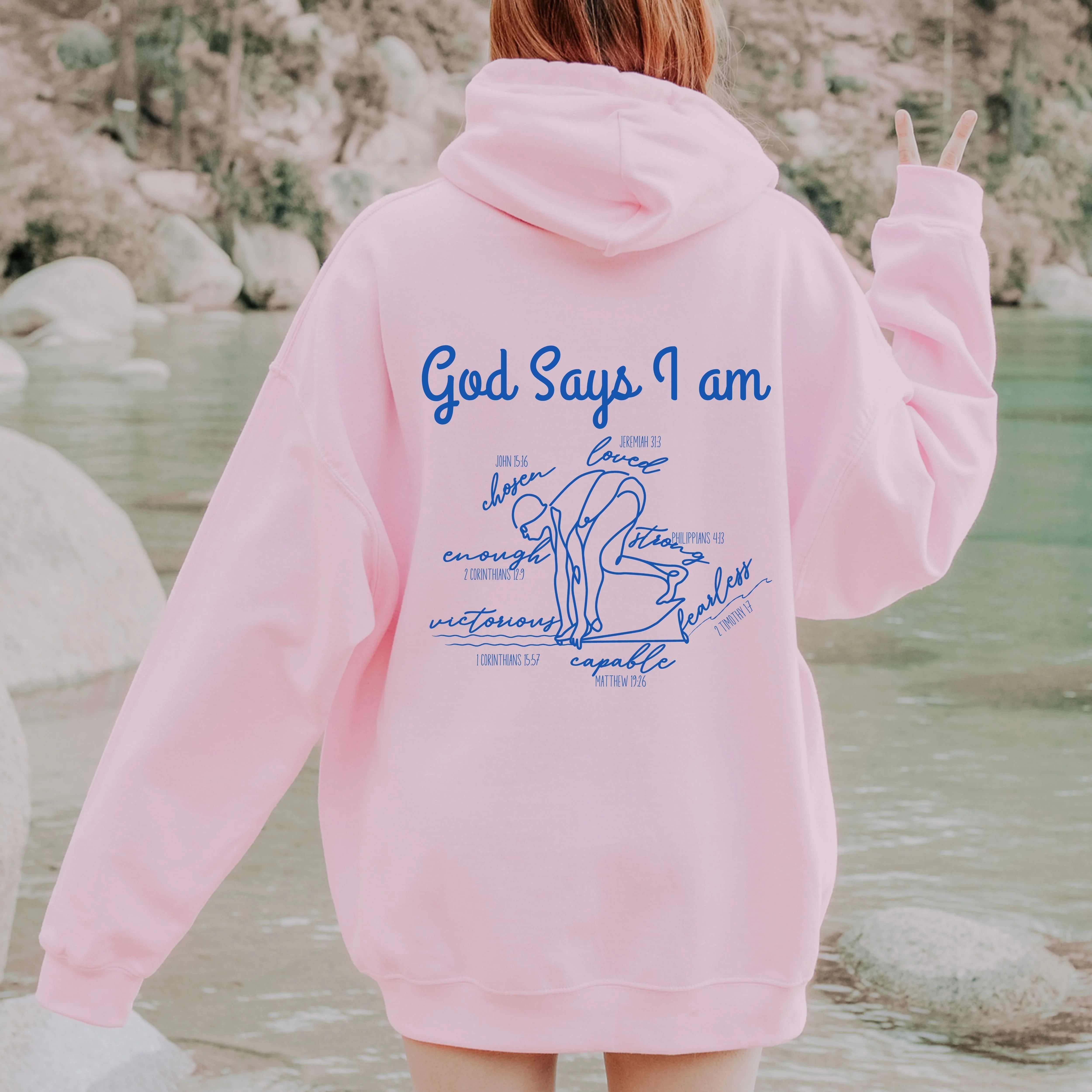 Person wearing a royal blue hoodie with God Says I am Faith based text and swimmer