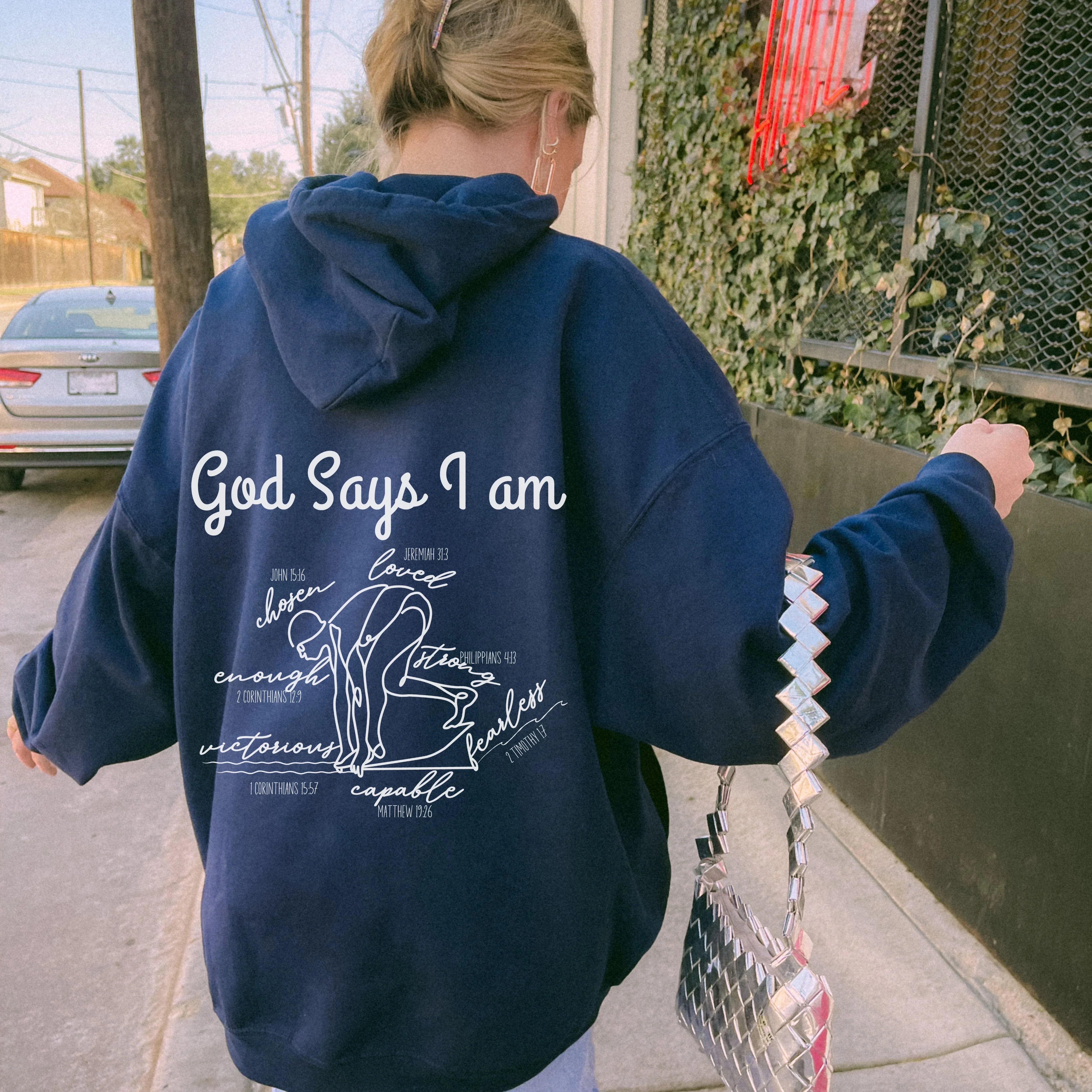 Person wearing a royal blue hoodie with God Says I am Faith based text and swimmer