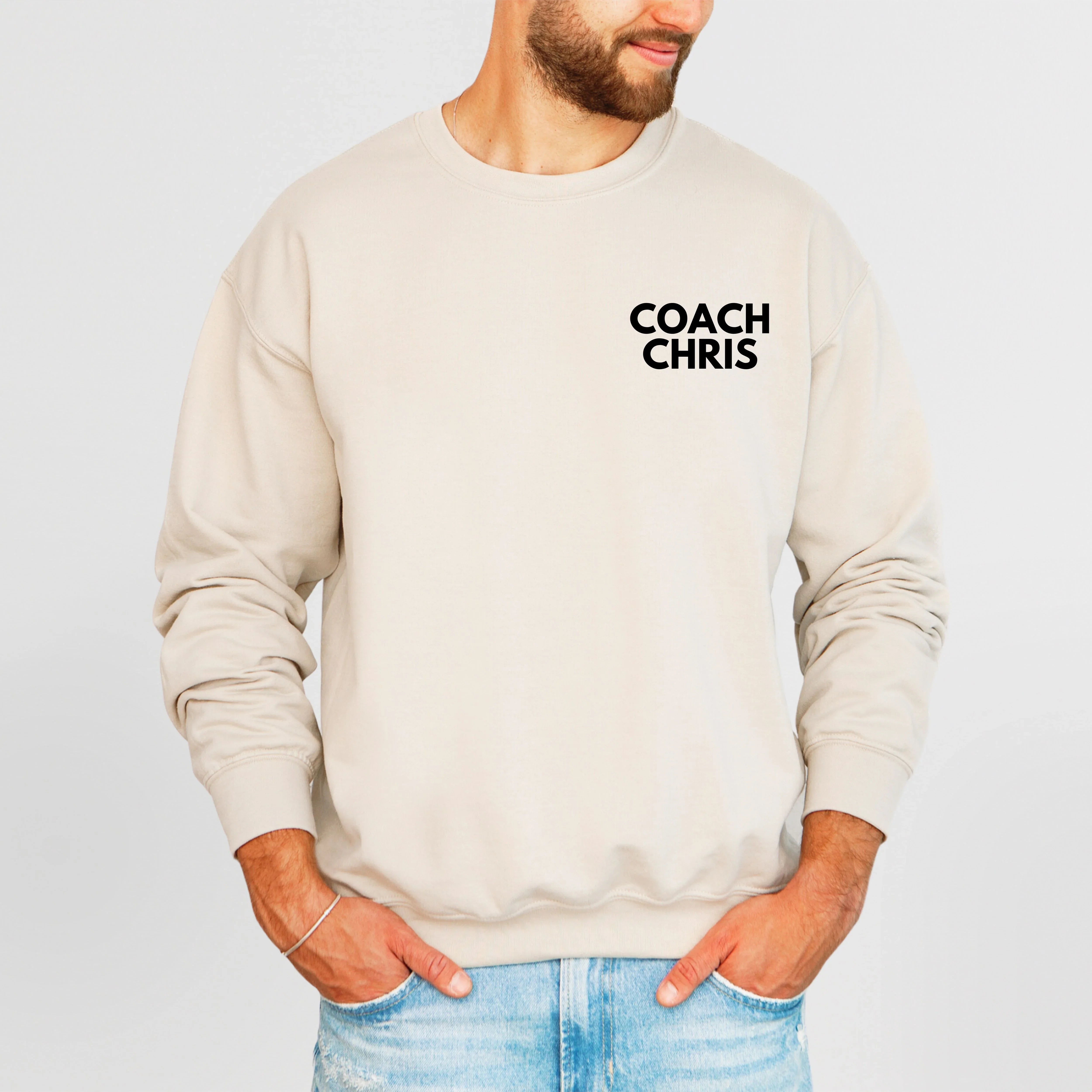 Beige sweatshirt with 'COACH CHRIS' text worn by a person on a light gray background