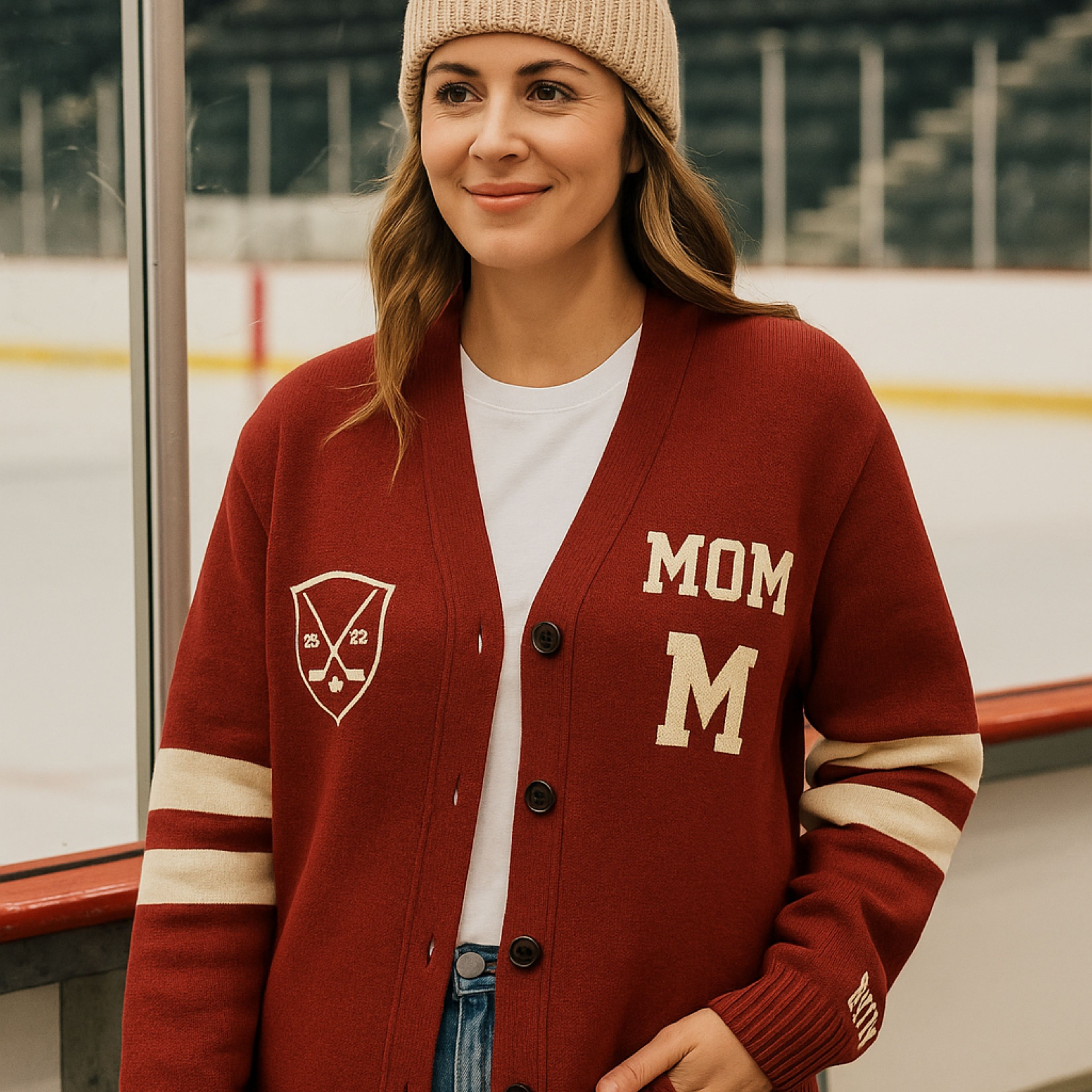 Woman in red varsity cardigan with 'MOM' lettering and knit beanie at ice rink