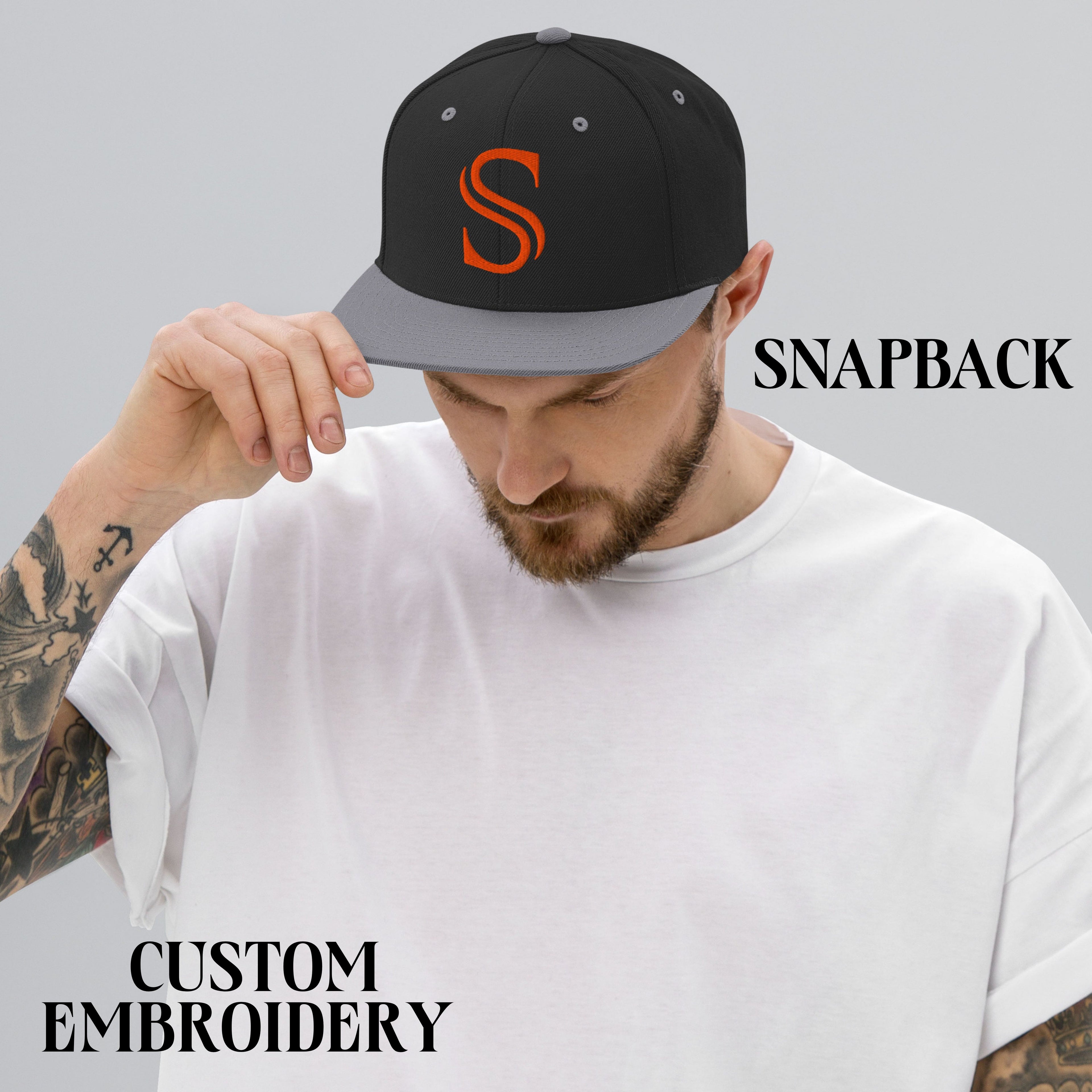 Man wearing black and gray snapback hat with orange embroidered S, custom embroidery apparel