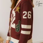 Maroon varsity cardigan with sports patches, football graphics, and number 26 on the sleeve