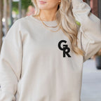 Person wearing a beige sweatshirt with 'GR' logo gymnastics