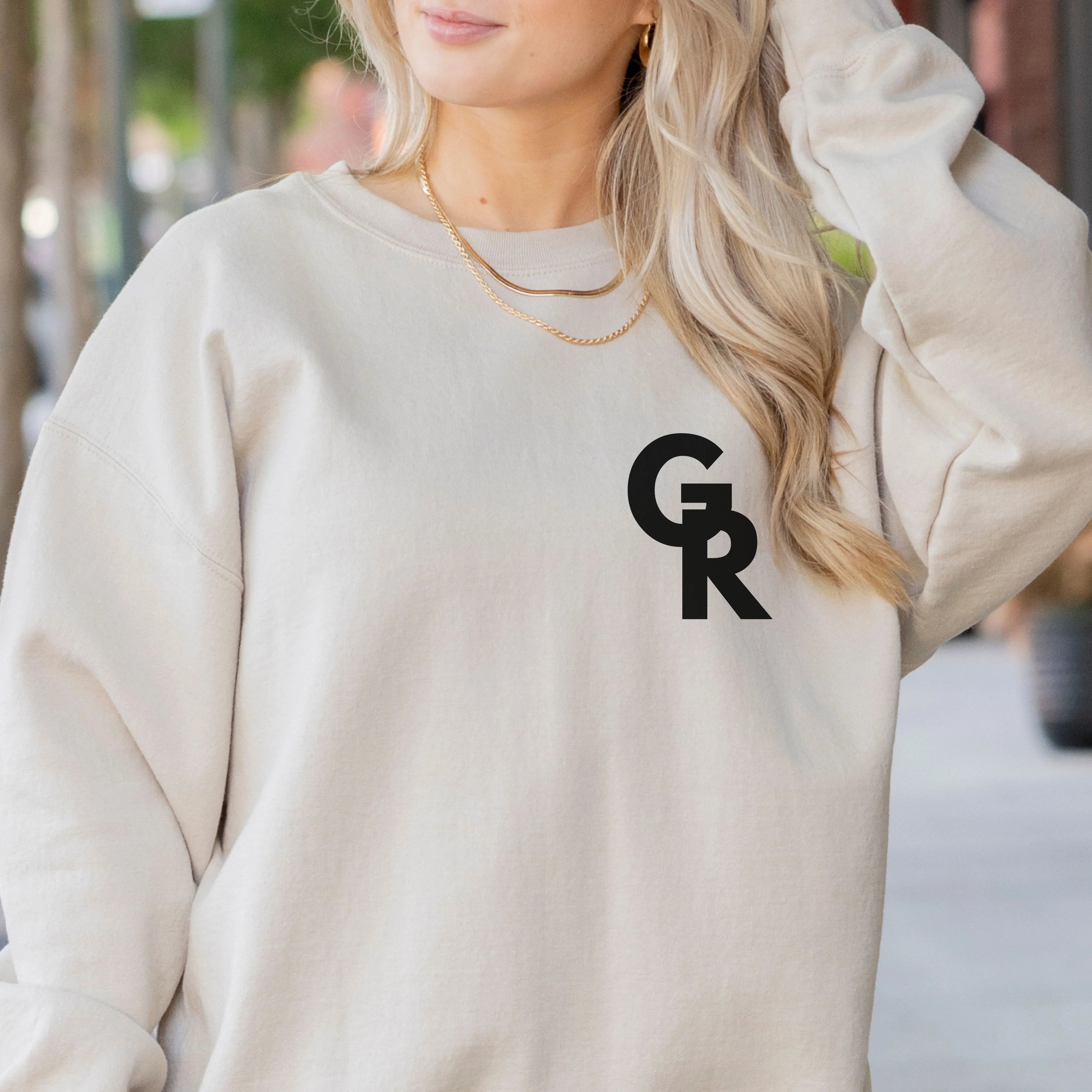 Person wearing a beige sweatshirt with 'GR' logo gymnastics