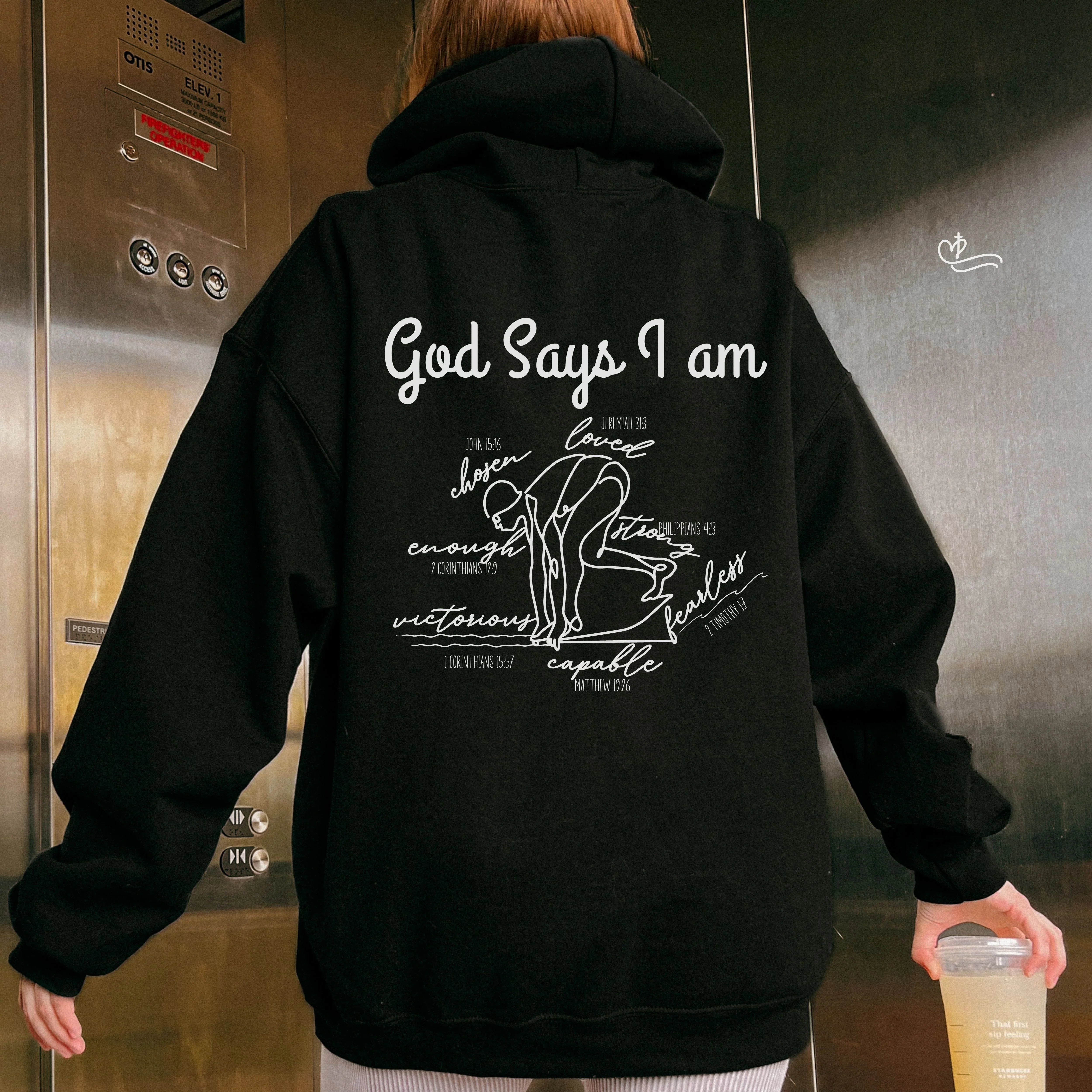 Person wearing a black hoodie with text and graphics on the back, standing in an elevator. God Says I Am Swimmer Faith Based Hoodie