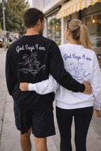 Two people wearing shirts with 'God Says I am' text, walking together on a sidewalk.