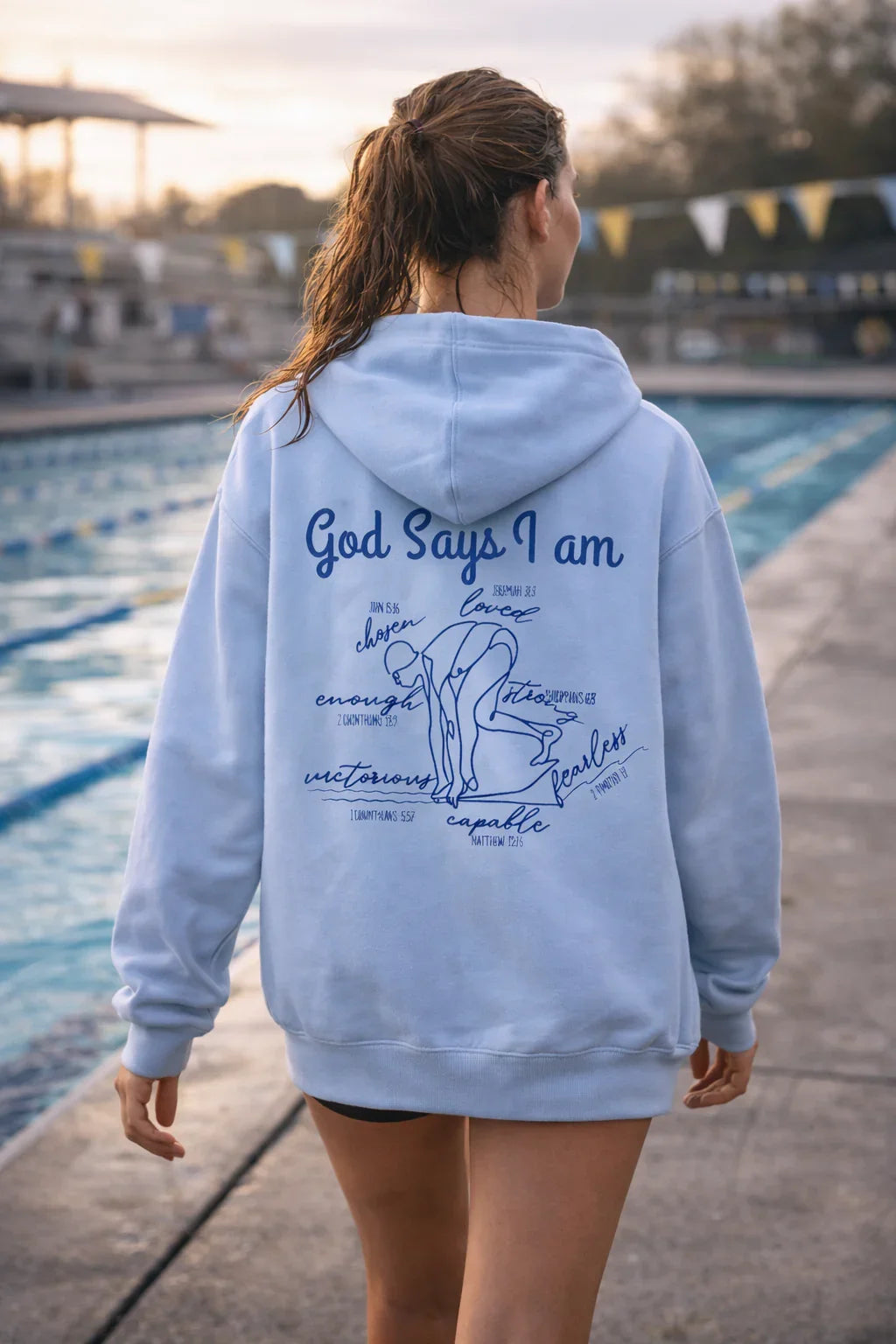 Person wearing a royal blue hoodie with God Says I am Faith based text and swimmer 