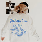 Person wearing a white sweatshirt with blue text God Says I am Swimmer and graphics on the back.