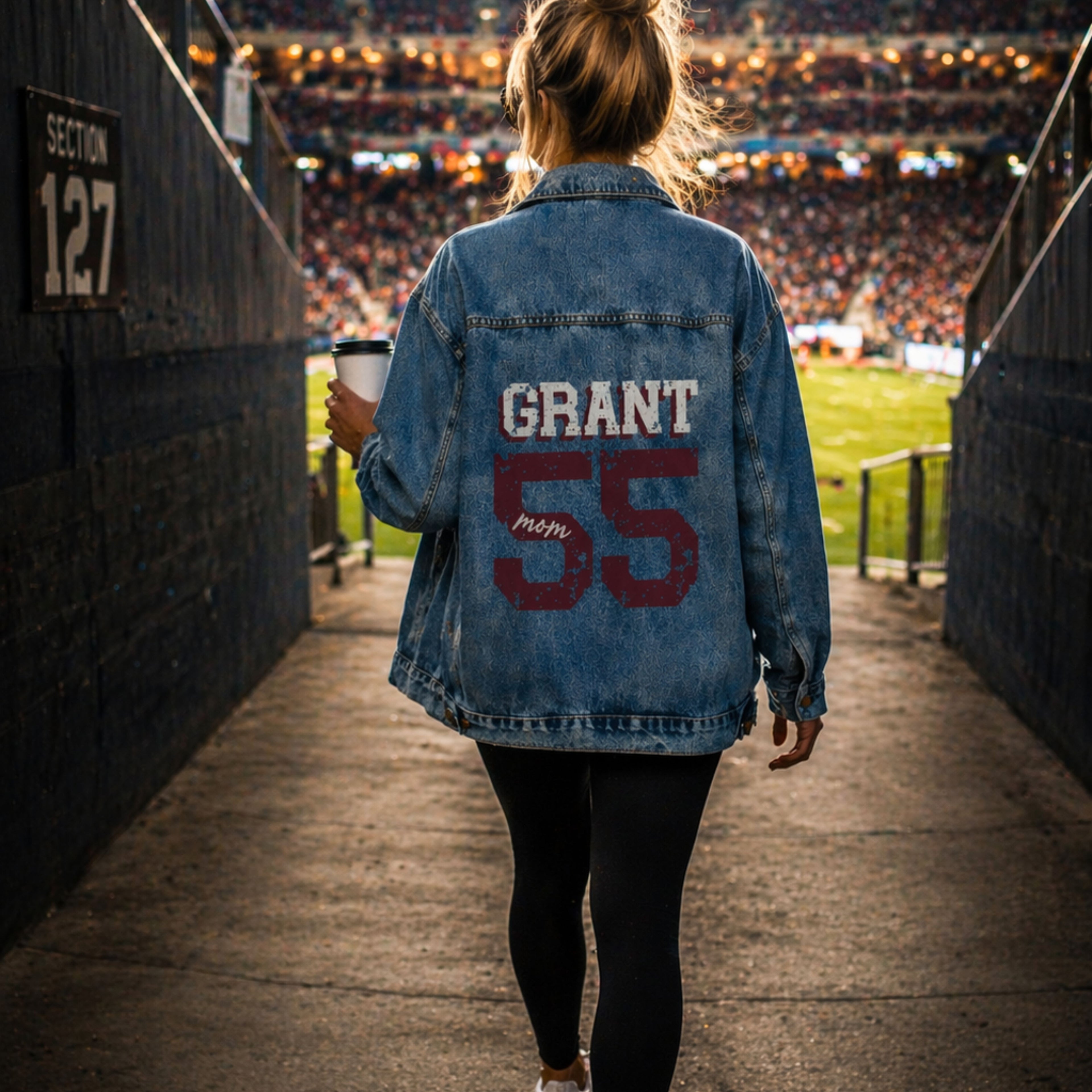 Person wearing a denim jacket with 'GRANT mom 55' at a sports event