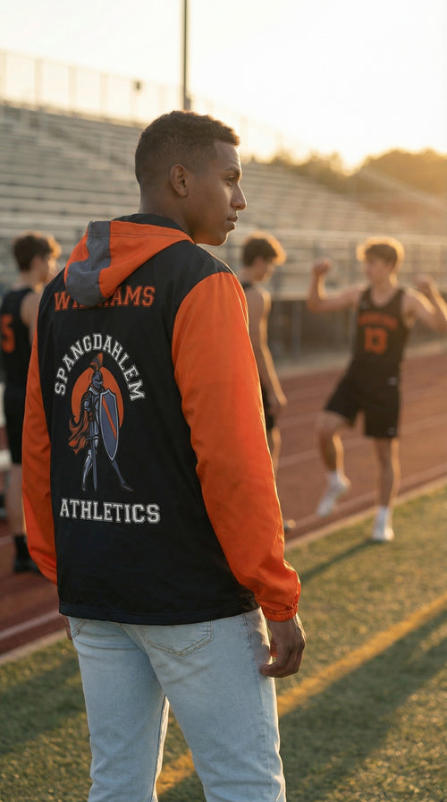 Person wearing a custom Athletics windbreaker jacket on a sports field with other people in the background.