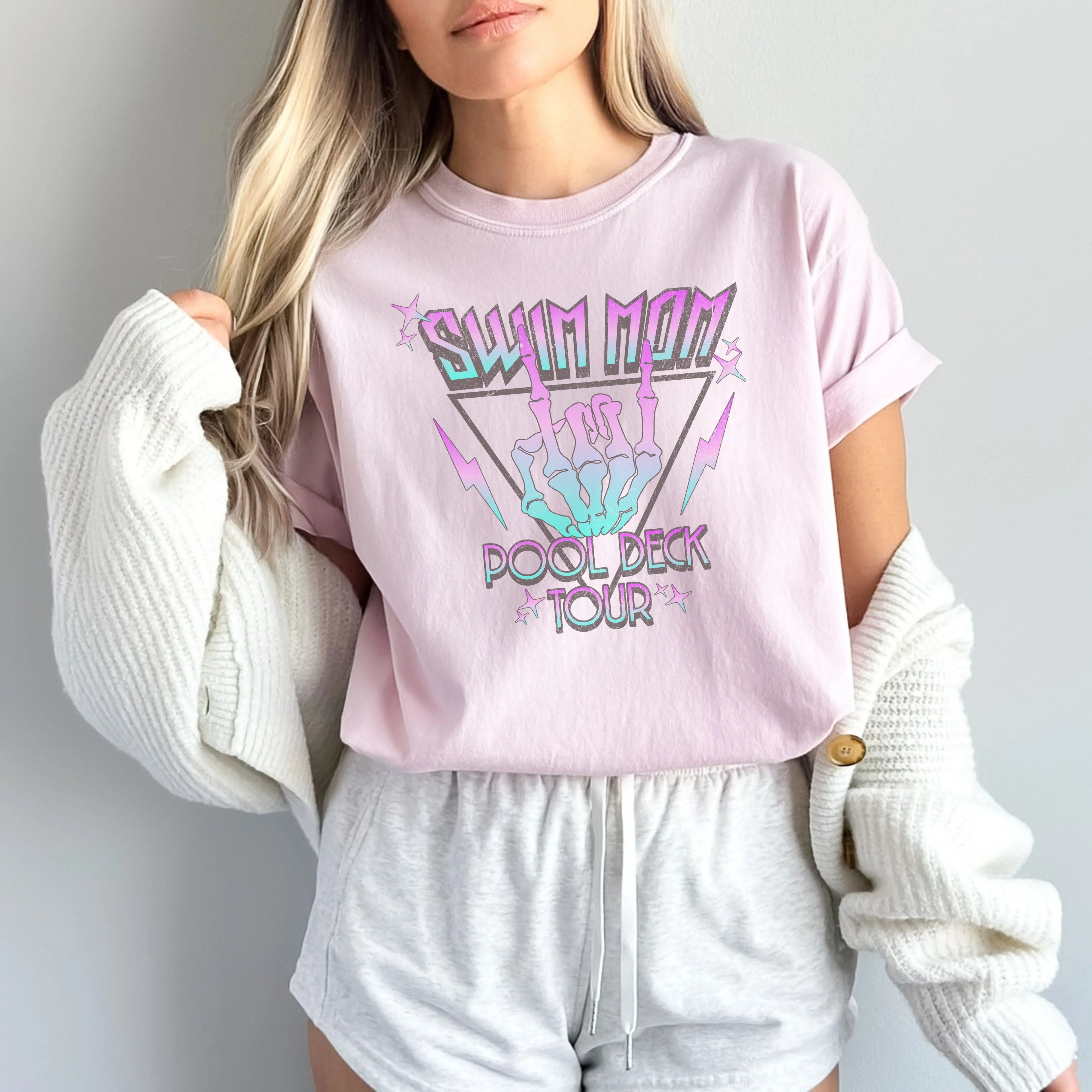 Person wearing a pink 'Swim Mom Pool Deck Tour' shirt with skeleton hands design.