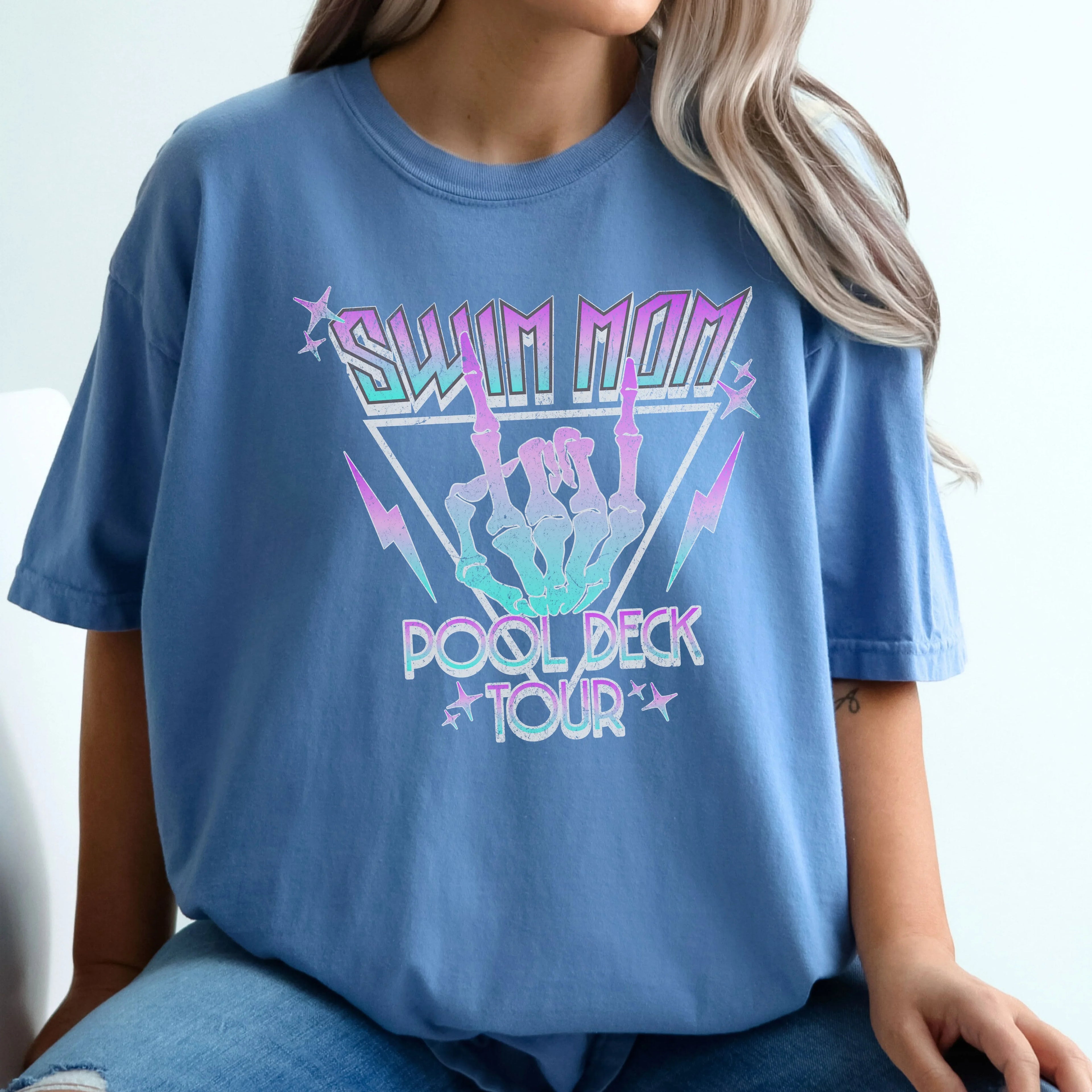 Person wearing a blue t-shirt with 'Swim Mom Pool Deck Tour' graphic design.