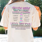 Person wearing a t-shirt with 'Swim Mom Makes it All Happen' text and graphics.