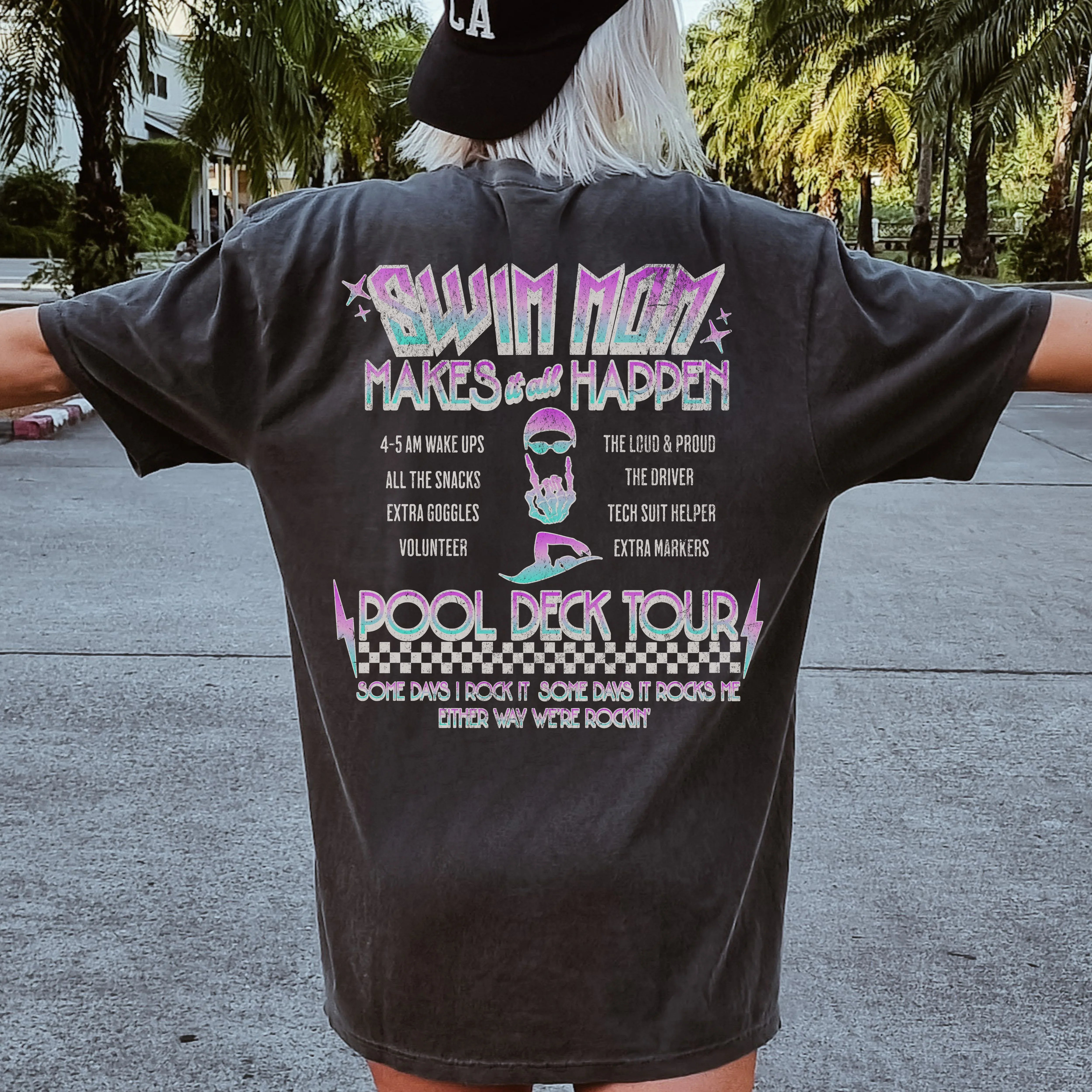 Person wearing a black t-shirt with colorful text and graphics on the back, standing outdoors.