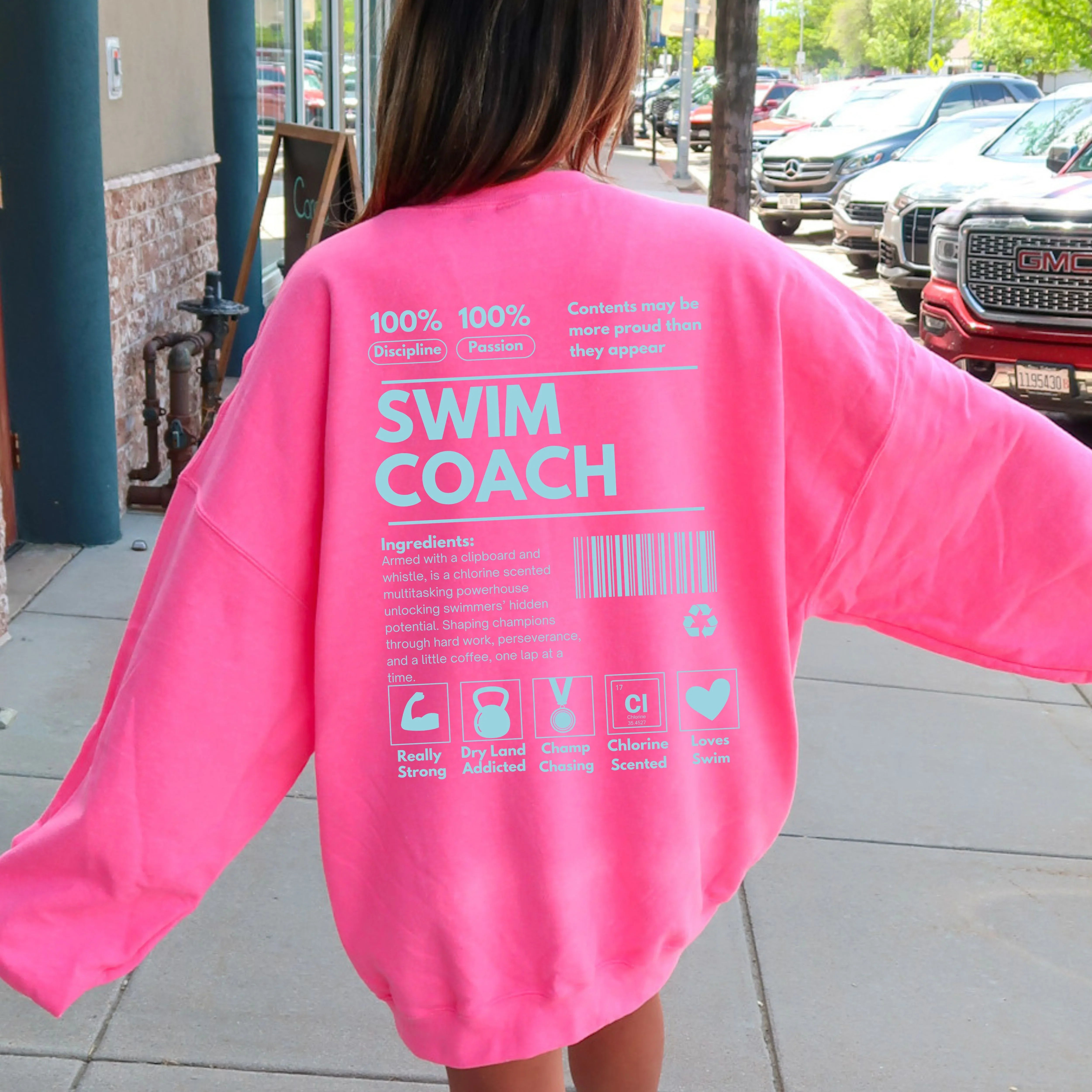 Person wearing a bright pink 'SWIM COACH' shirt outdoors.